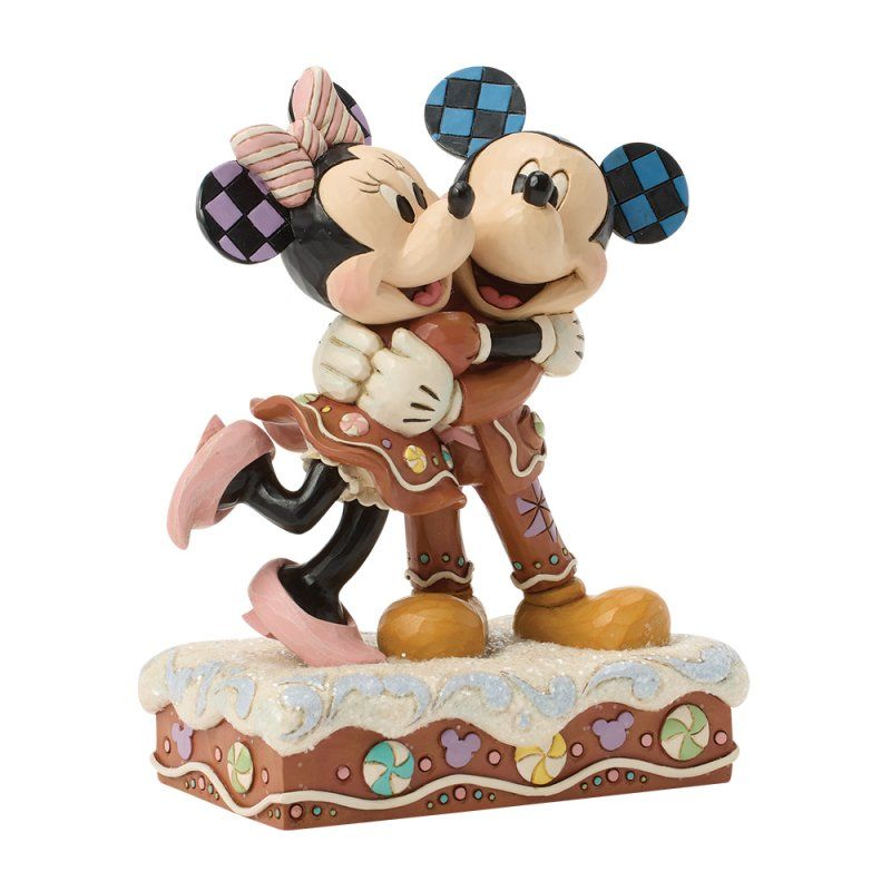 Mickey en Minnie Mouse omhelzen elkaar, in de vorm van peperkoekfiguurtjes, op een versierde sokkel.