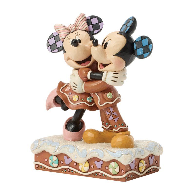 Een beeldje van Mickey en Minnie Mouse die elkaar omhelzen, in de vorm van peperkoek, op een versierde sokkel.