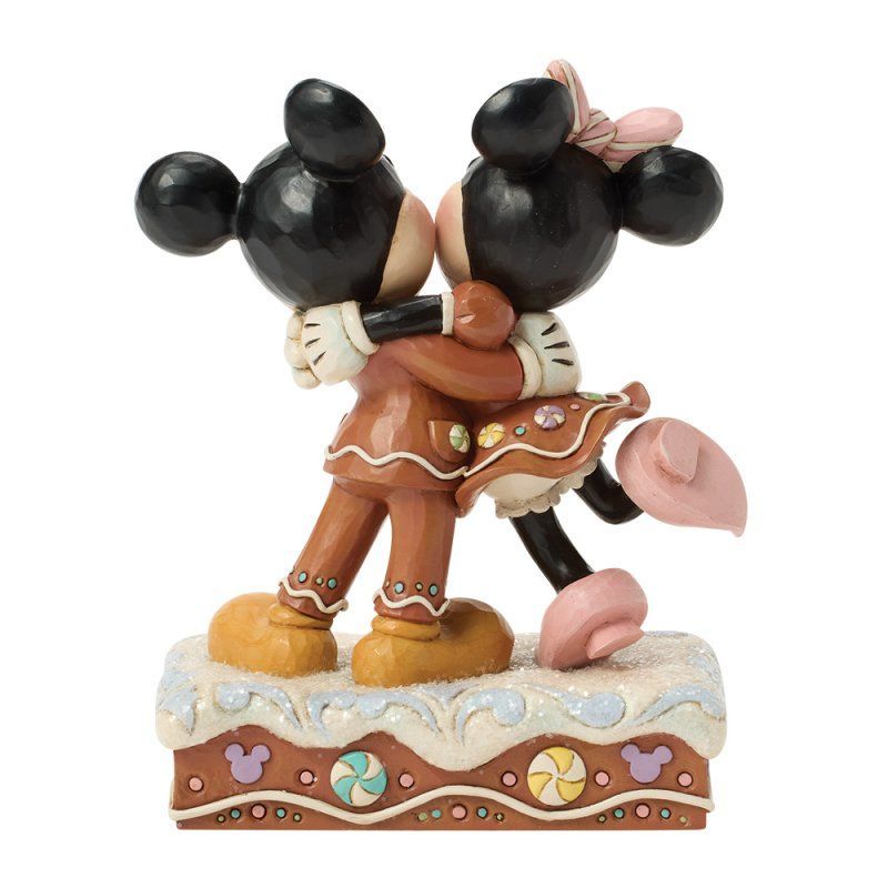 Mickey en Minnie Mouse in peperkoekpakjes omhelzen elkaar op een met glazuur bedekte ondergrond.