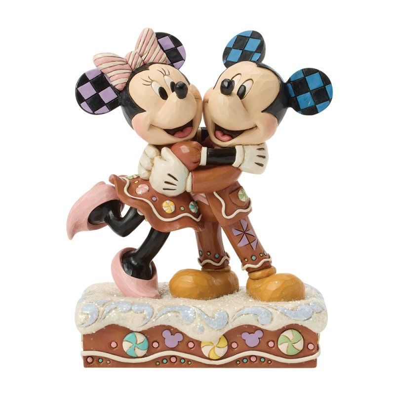Mickey en Minnie Mouse omhelzen elkaar, in de vorm van peperkoekfiguurtjes, op een versierde sokkel.