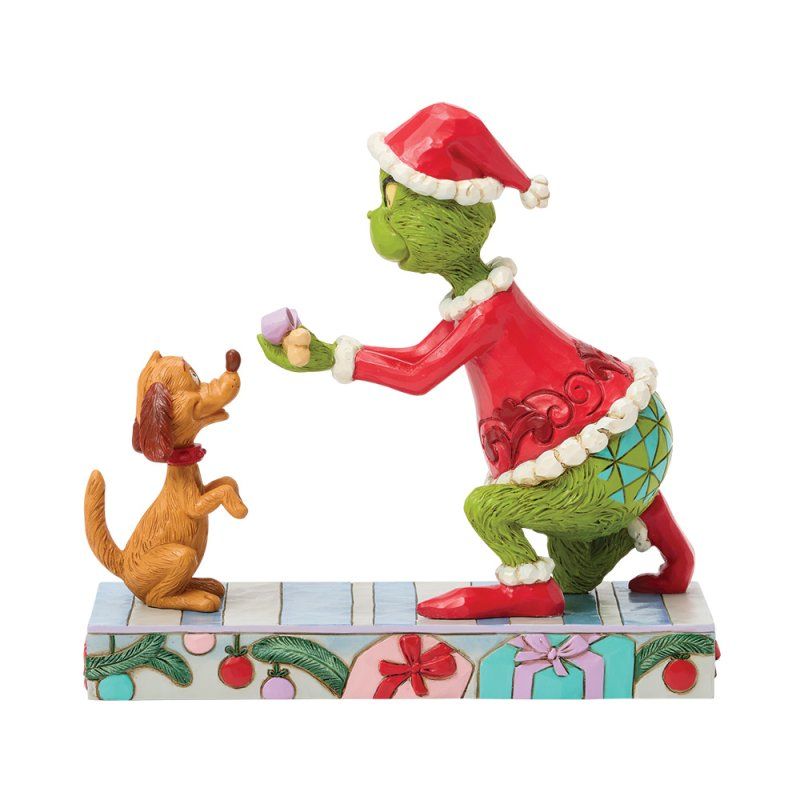 De Grinch in een kerstmanpak biedt een cadeautje aan zijn hond aan, op een decoratieve sokkel met kerstcadeaus.