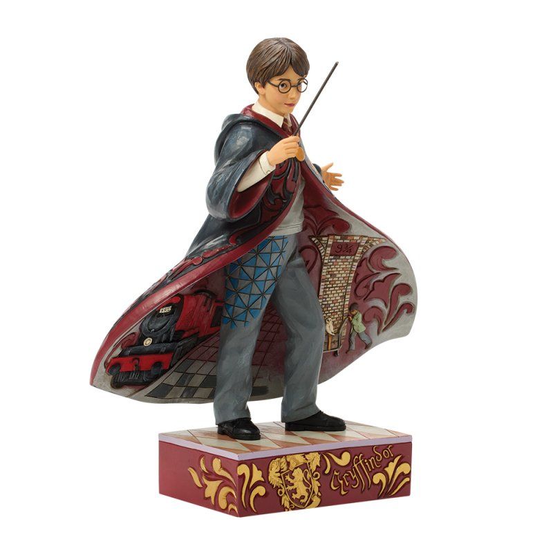 Een Harry Potter-figuurtje, met toverstaf in de hand en gekleed in een gewaad met sleep, staat op een versierde sokkel.
