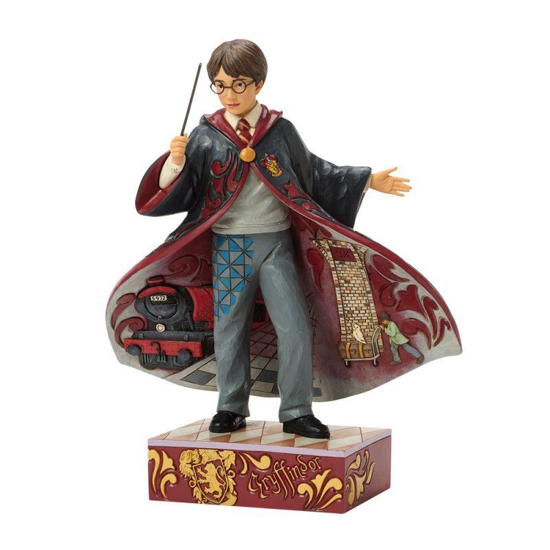 Een Harry Potter-figuurtje, met toverstaf in de hand en gekleed in een gewaad met sleep, staat op een versierde sokkel.