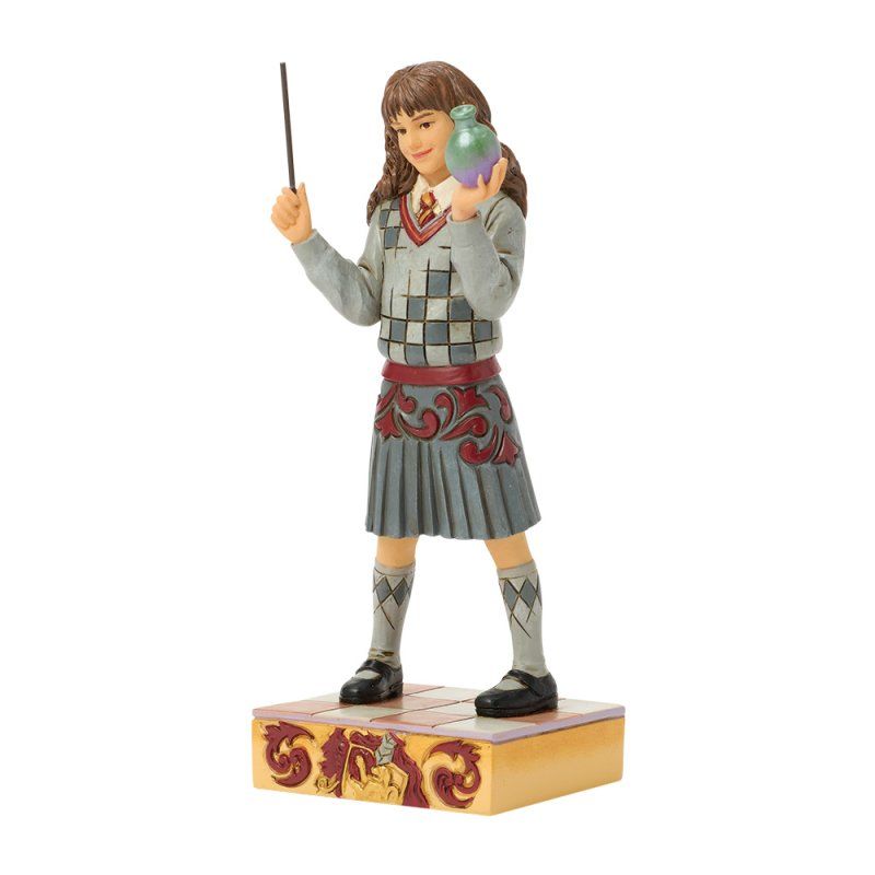 Figuur van een persoon met een toverstaf en een toverdrank, gekleed in een grijs uniform met rode accenten, staand op een decoratieve sokkel.