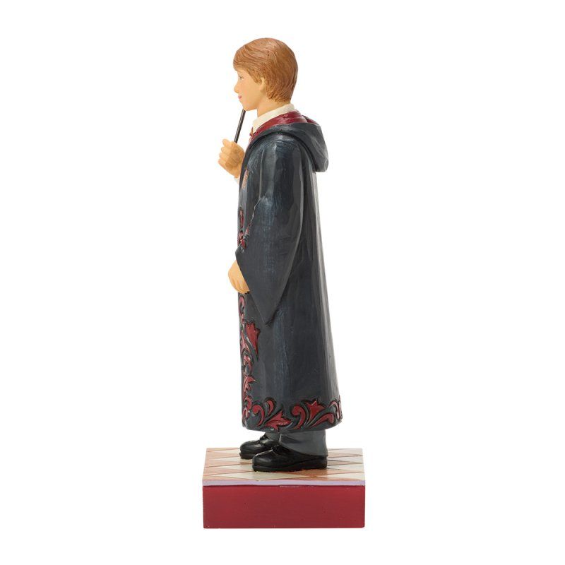 Een beeldje van Ron Weasley in tovenaarsgewaad, met toverstaf in zijn hand, staand op een sokkel.