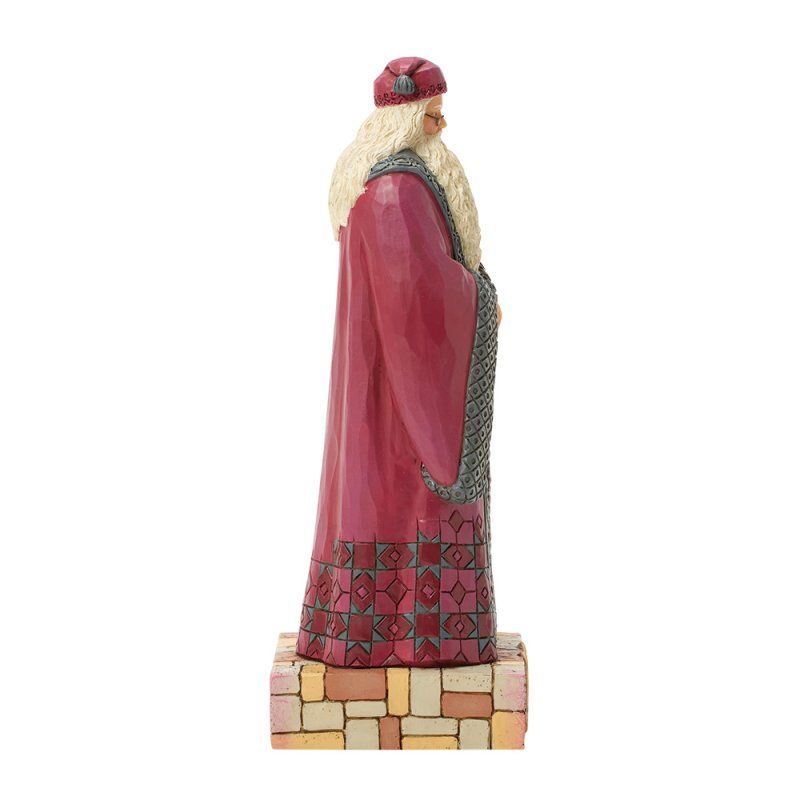 Een kerstmanfiguur in een rode mantel met een lange witte baard, op een baksteenachtige sokkel.