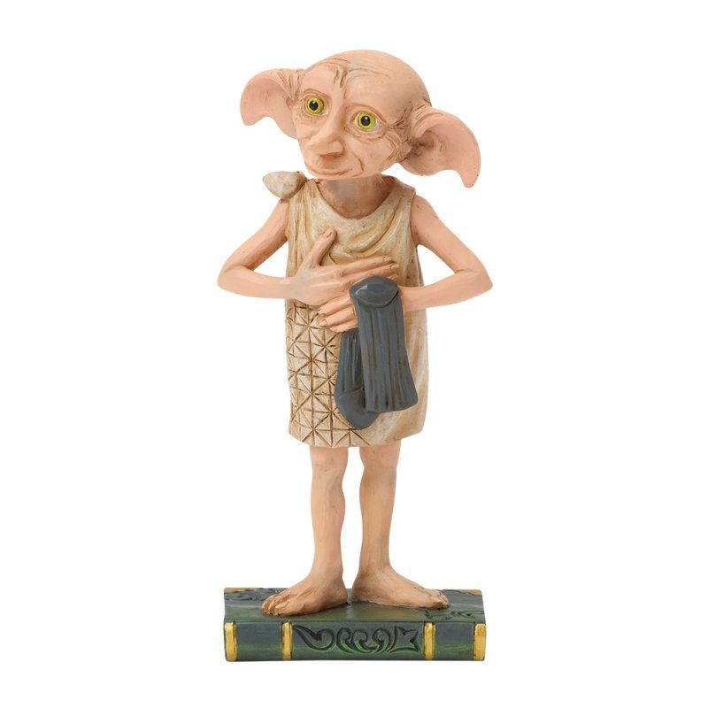 Het beeldje van Dobby de huiself, met een donkergrijs gewaad in zijn handen, staat op een boekvormige sokkel.