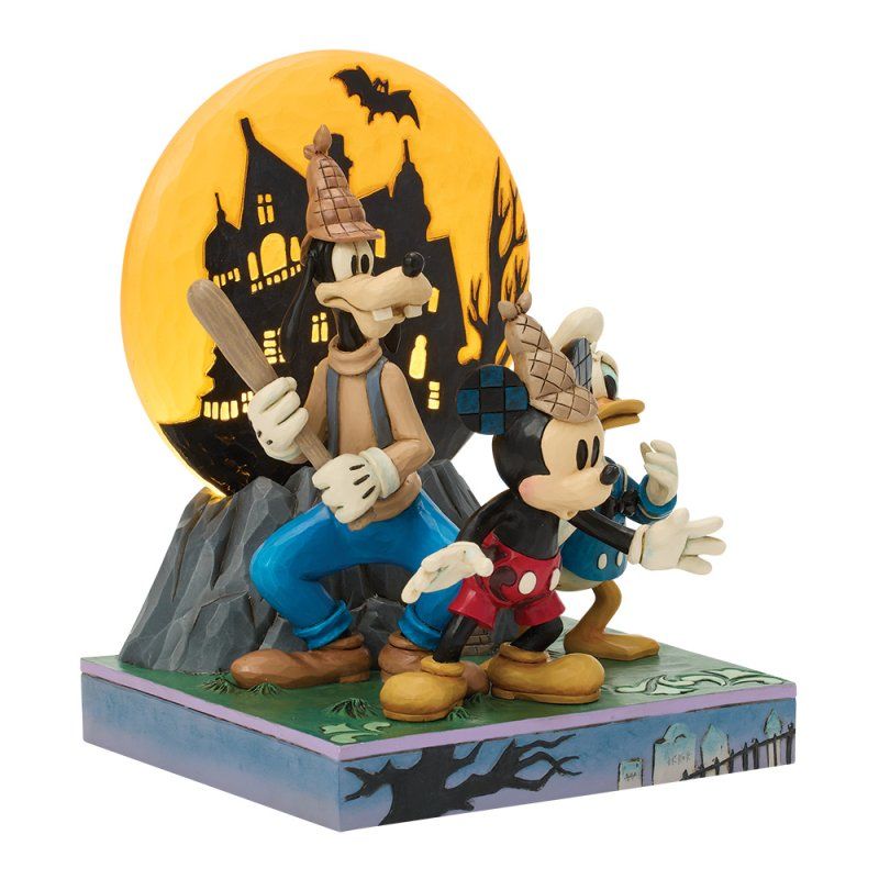 Goofy, Mickey en Donald in Halloweenkostuums met een griezelig kasteel en een maan op de achtergrond.