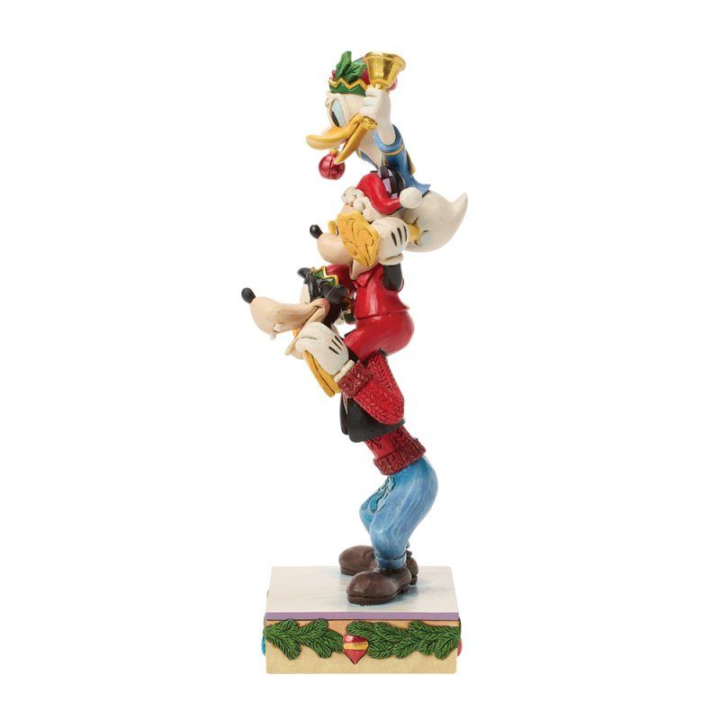 Kerstfiguren van Disney op een gestapelde ondergrond: Donald Duck, Goofy en Mickey Mouse, op een versierde sokkel.