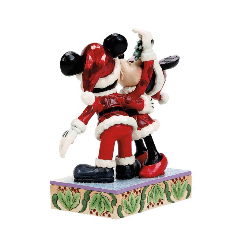 Mickey en Minnie Mouse in kerstmanpakjes kussen elkaar, op een sokkel met een kerstthema.