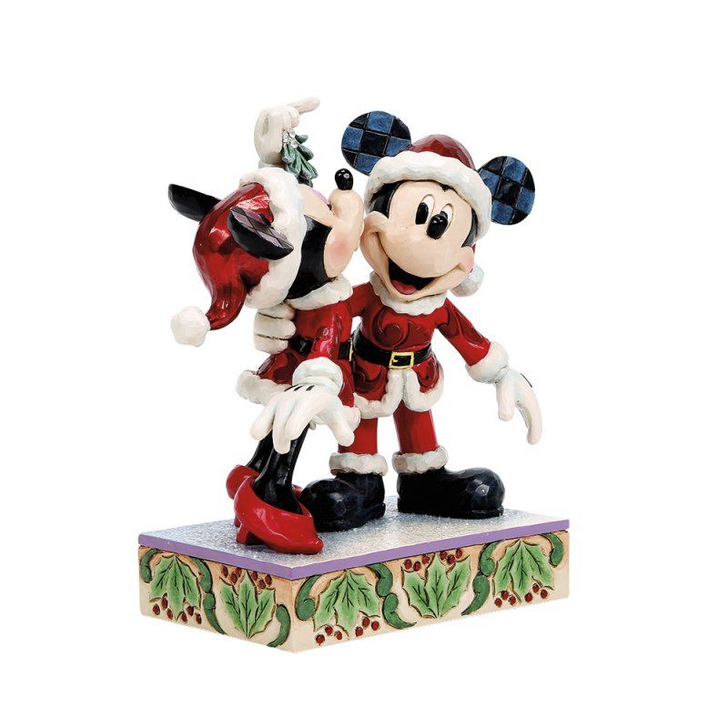 Mickey en Minnie Mouse in kerstmanpakjes kussen elkaar onder een maretak, staand op een versierde sokkel.