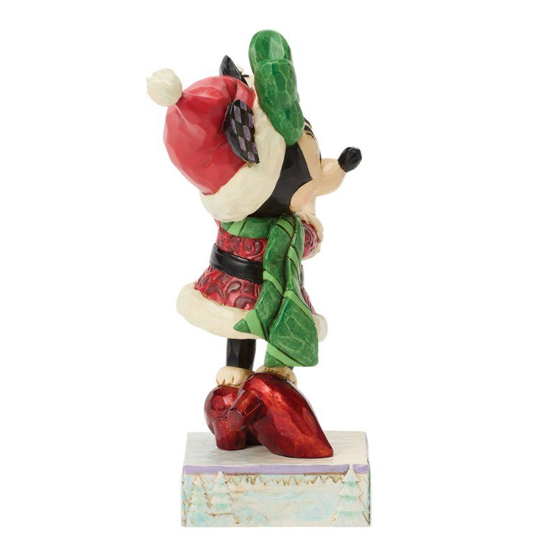 Een Minnie Mouse-figuurtje in een rode feestoutfit, staand op een besneeuwde sokkel.
