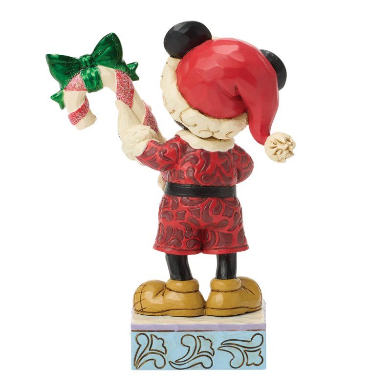Een Mickey Mouse-figuurtje in een kerstmanpak, met een zuurstok in zijn hand, van achteren gezien.