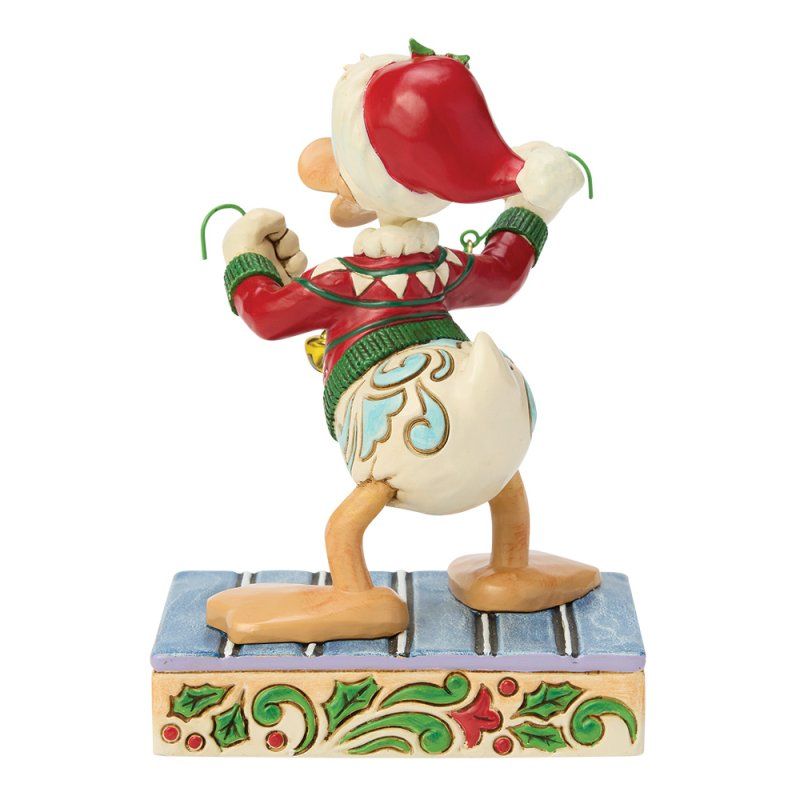 Een Donald Duck-figuurtje met kerstmuts en -trui, dansend op een podium met een patroon.