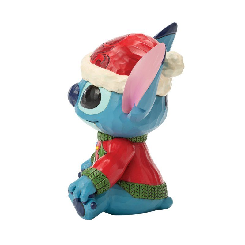 Een Stitch-figuurtje met een rode kerstmuts en trui, die opzij kijkt.