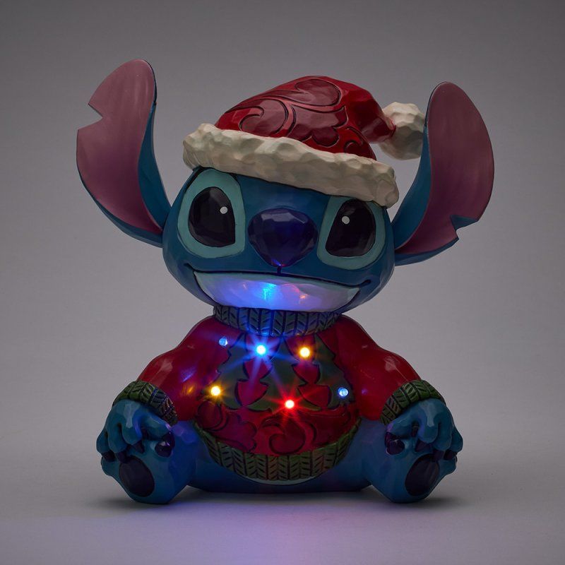 Een Stitch-figuurtje met een kerstmuts en een kersttrui, versierd met veelkleurige lichtjes.