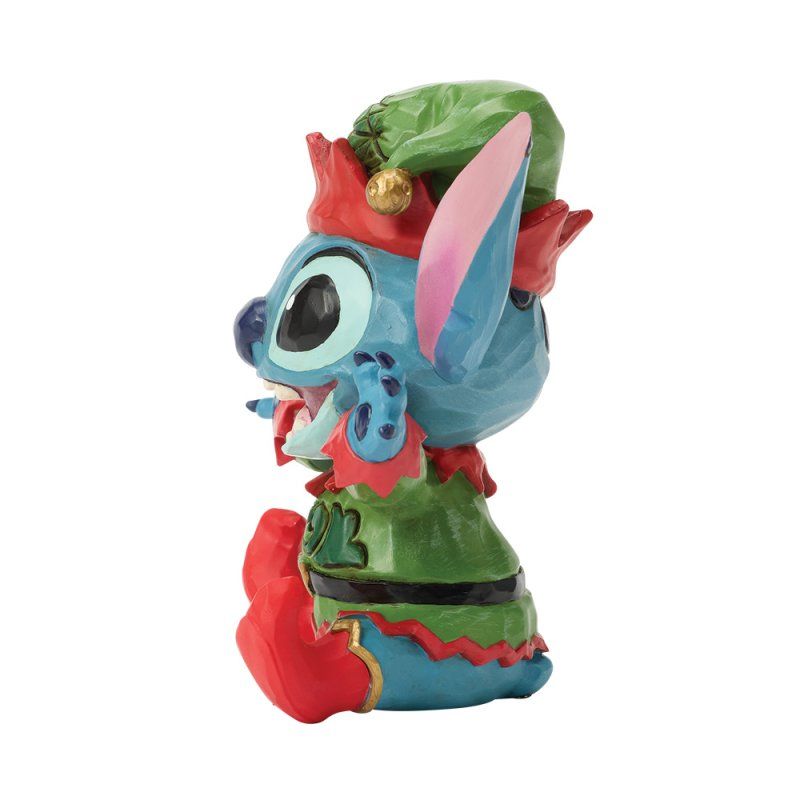 Een beeldje van Stitch in elfenkleding, blauw met rood en groen, met een lachend gezicht.