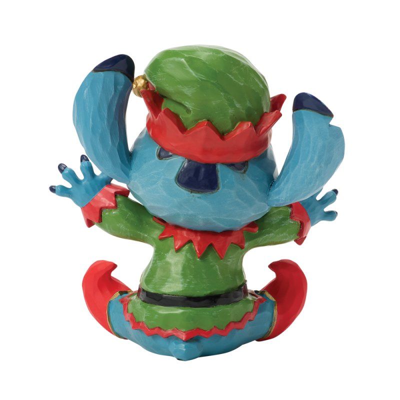 Stitch verkleed als elf, in een blauw met groen en rood pak, met zijn armen omhoog en een vrolijke uitdrukking.