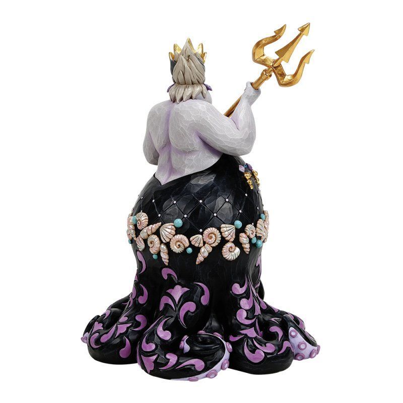 Beeldje van Ursula met een gouden drietand, van achteren gezien, in een paarse en zwarte jurk.
