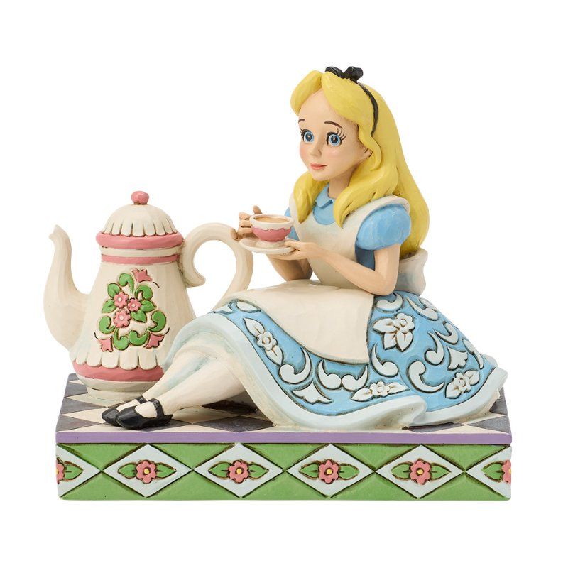 Een beeldje van Alice uit Alice in Wonderland met een theekopje, zittend naast een theepot, op een decoratieve sokkel.