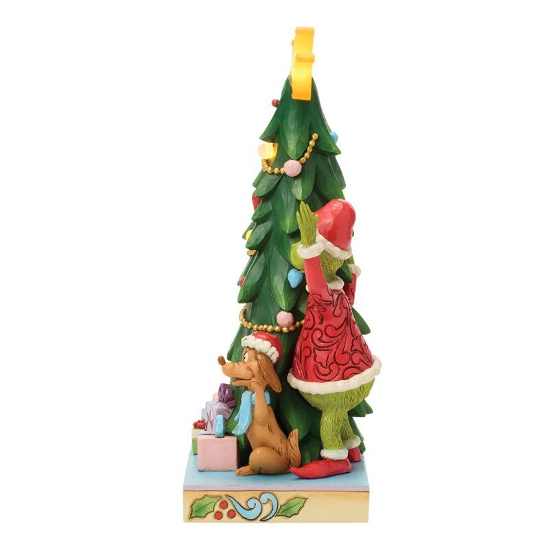 De Grinch steelt kerstversieringen uit de boom, terwijl de hond toekijkt.
