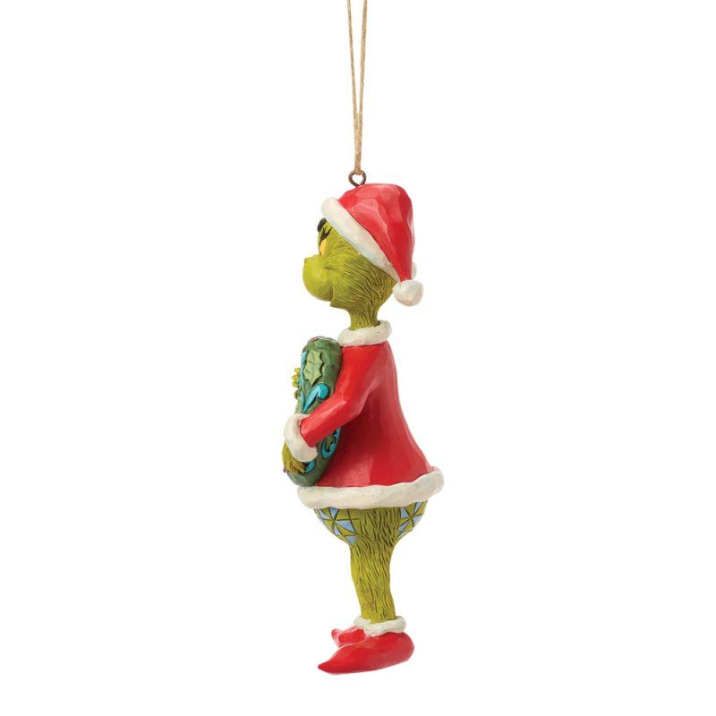 Een kerstornament van de Grinch in een rood kerstmanpak, met een blauwgroen voorwerp in zijn hand; zijaanzicht.