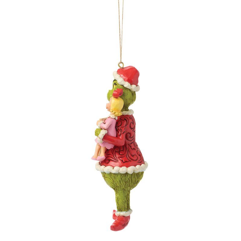 Een kerstmanfiguur van de Grinch in een kerstmanpak, die een klein meisje in een roze jurk vasthoudt. Groen lijf, rode jas.