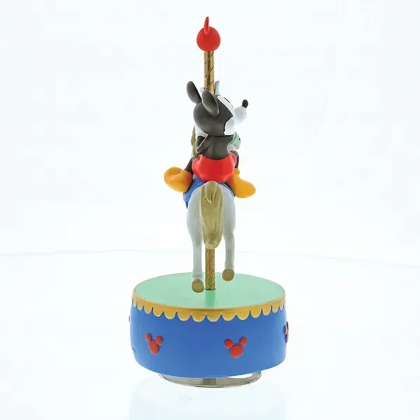 Een Mickey Mouse-figuurtje rijdend op een carrouselpaard, bovenop een blauwe muziekdoos als voetstuk.