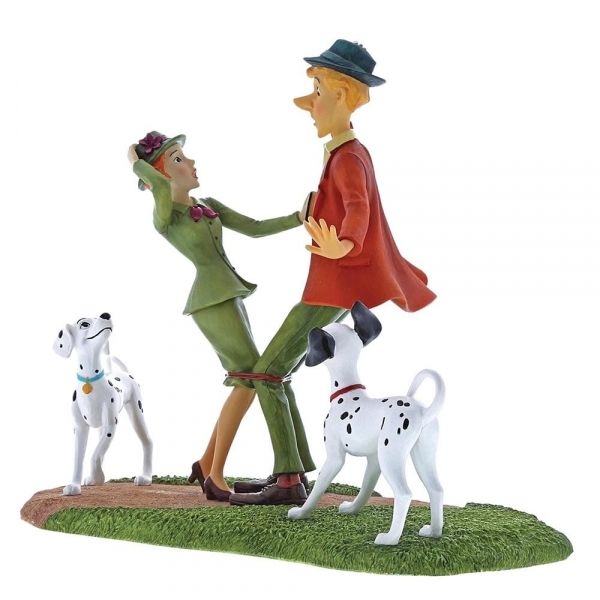 Beeldje van een man en een vrouw in formele kleding met twee Dalmatiërs op een grasveld.