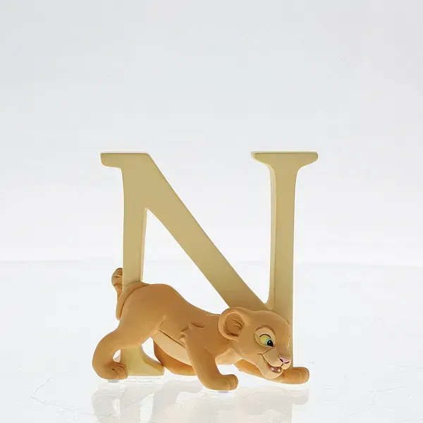 Leeuwenwelpje Nala klampt zich vast aan een crèmekleurige letter 