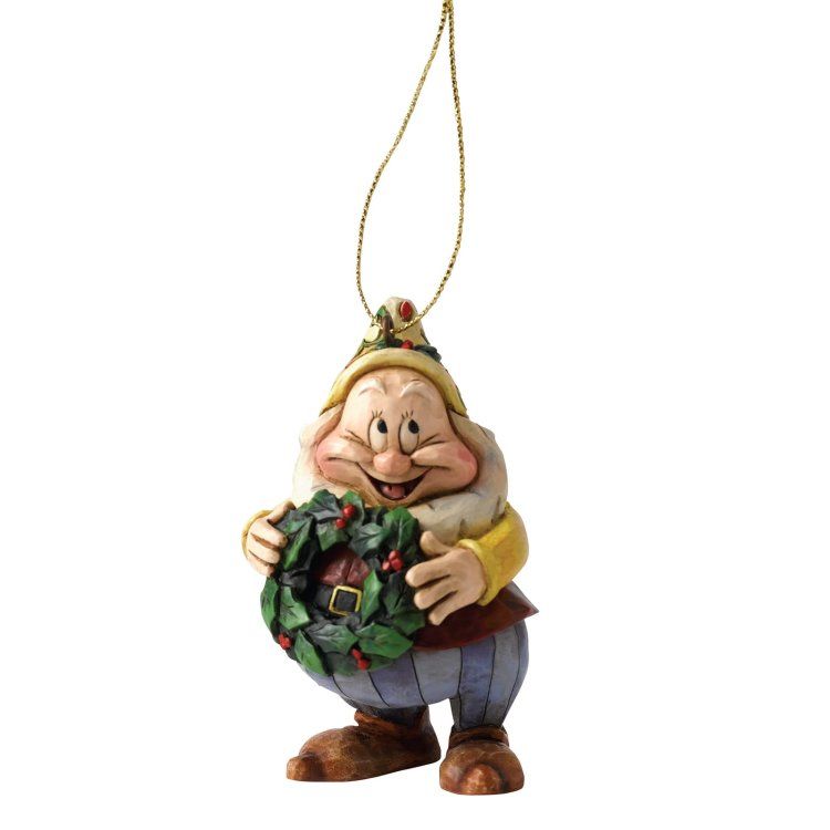 Een sullig kerstornament met een krans in zijn hand, lachend. Hij draagt ​​een geel shirt, een groene hoed en een blauwe broek.
