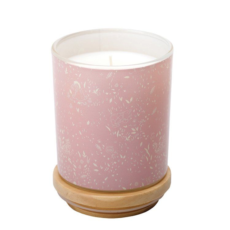Roze gespikkelde kaars in een glazen pot, die op een houten voetstuk staat.