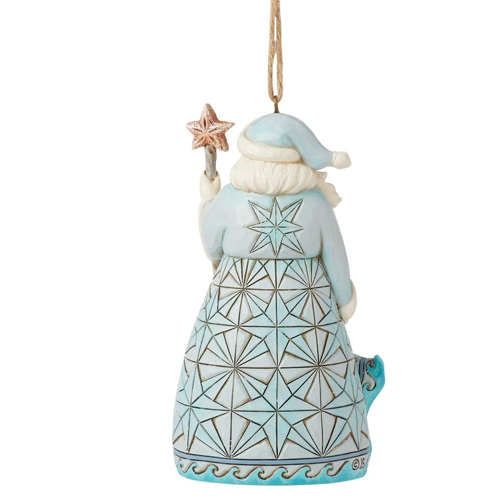 Ornament van de kerstman in blauwe gewaden, met staf, tegen een strandscène.
