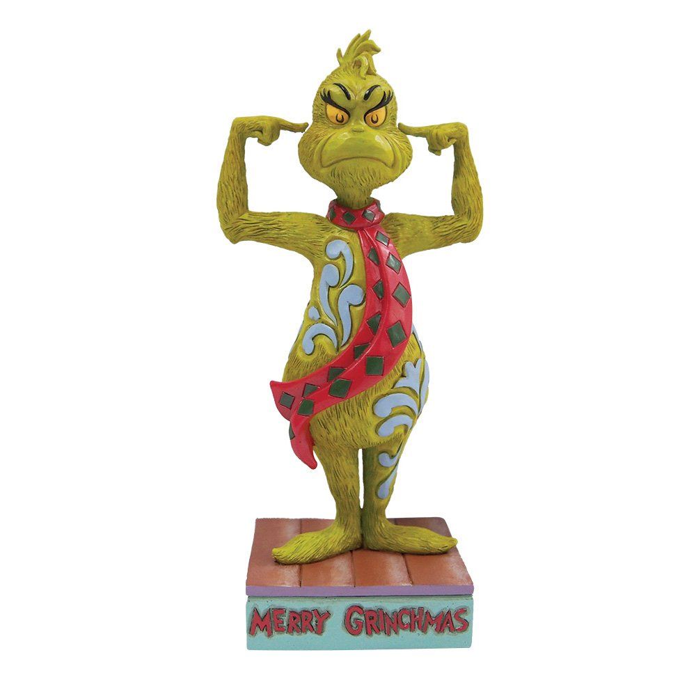 Een standbeeld van de Grinch, met zijn oren bedekt en een sjaal om, staat op een blok met de tekst