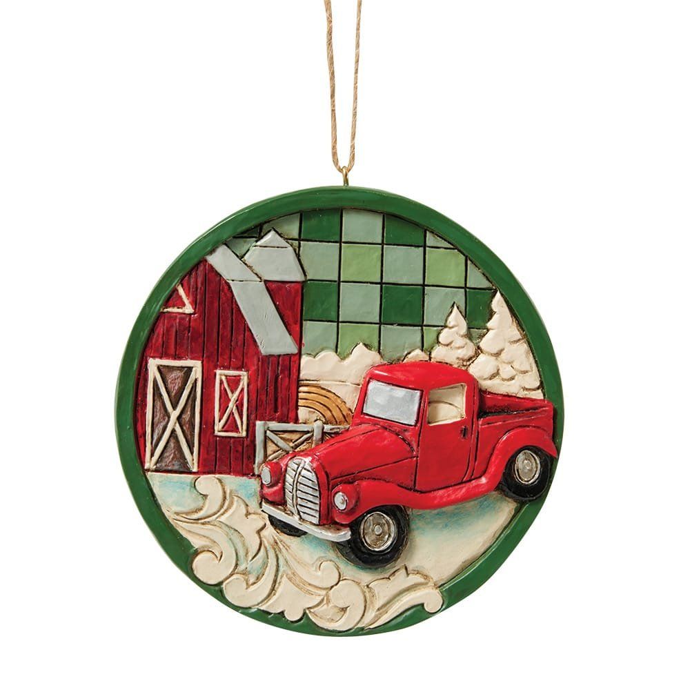 Ornament in de vorm van een rode vrachtwagen met een schuur, bomen en een groene achtergrond.
