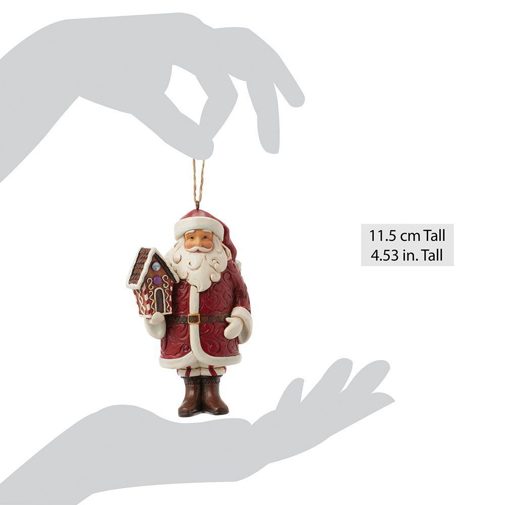 Een kerstmanfiguur met een peperkoekhuisje in zijn handen, gekleed in een rode jas en muts.