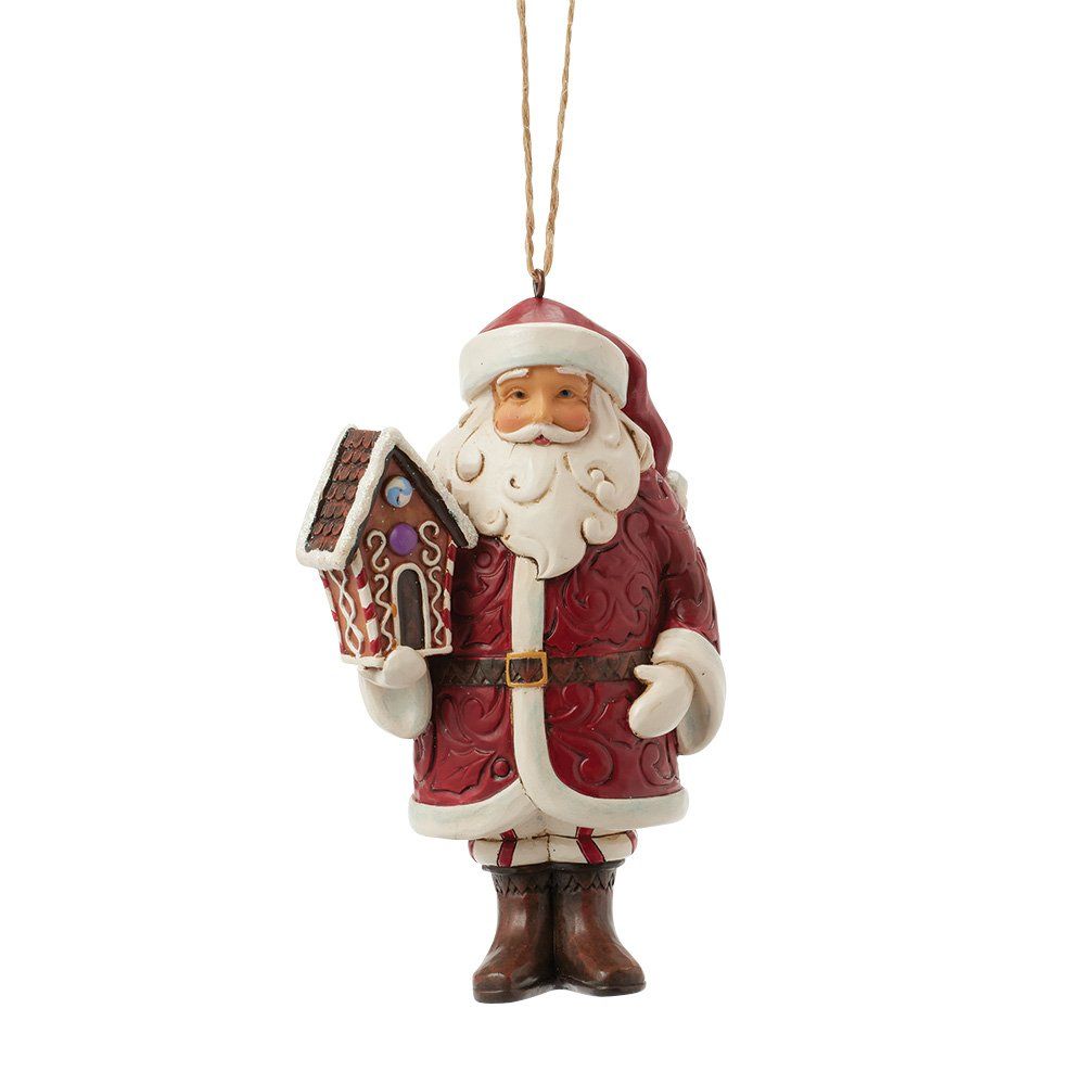 Een kerstmanfiguur met een peperkoekhuisje in zijn handen, gekleed in een rode jas en muts.