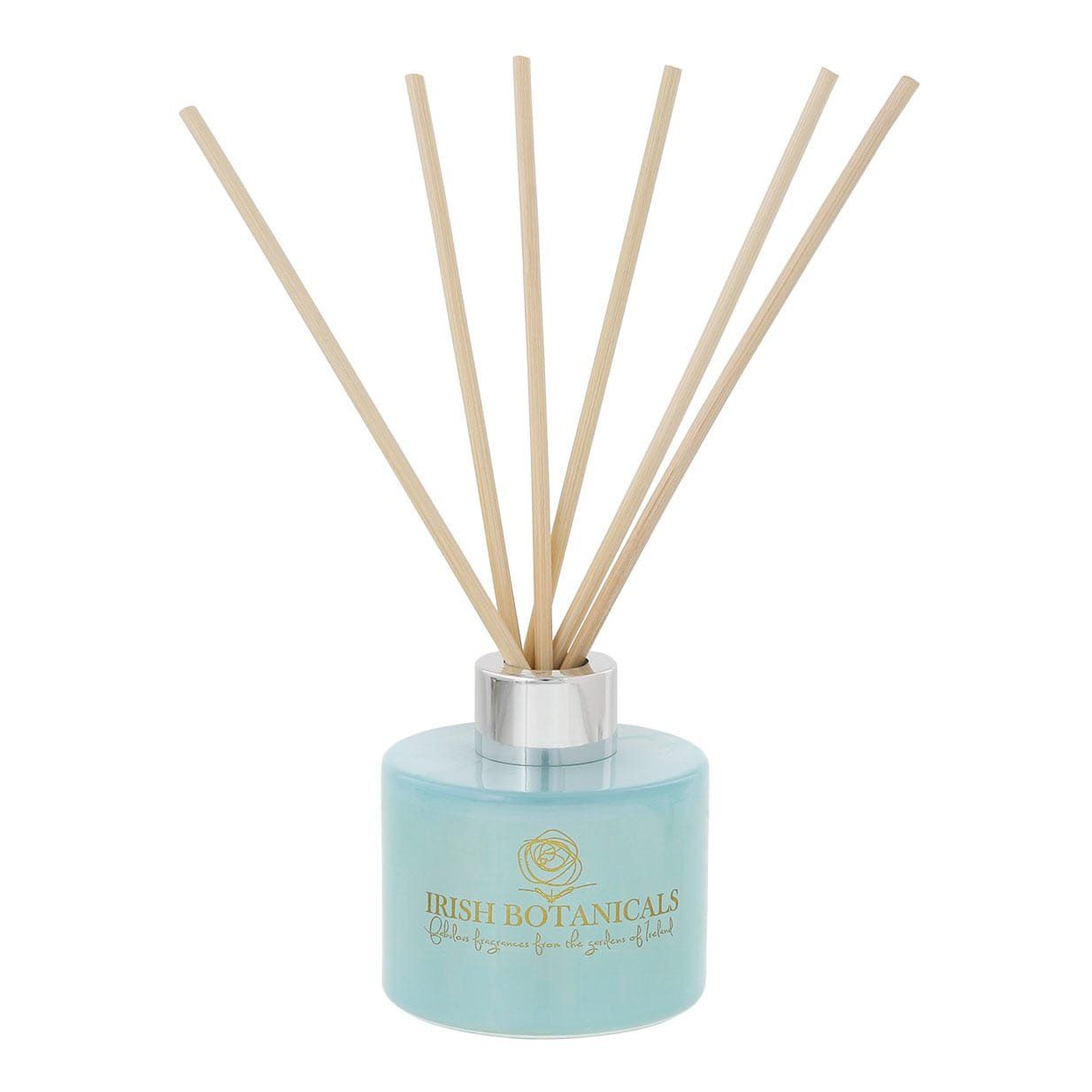Blauwe rietdiffuser met beige rietjes, een zilveren kraag en gouden tekst.