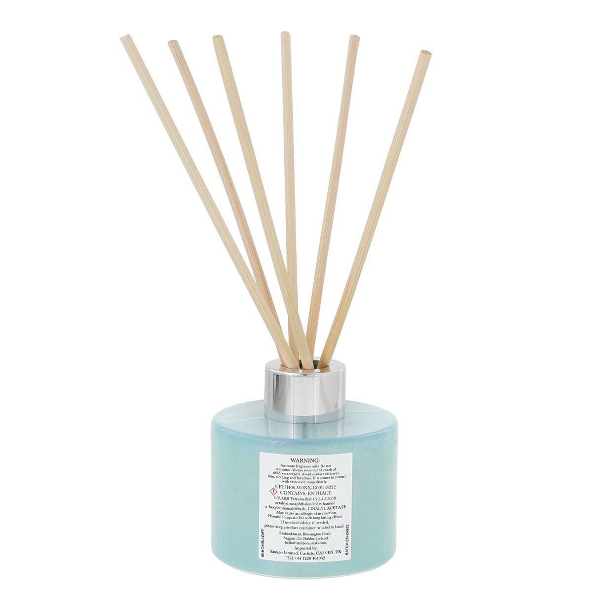 Blauwe rietdiffuser met beige rietjes, een zilveren kraag en gouden tekst.