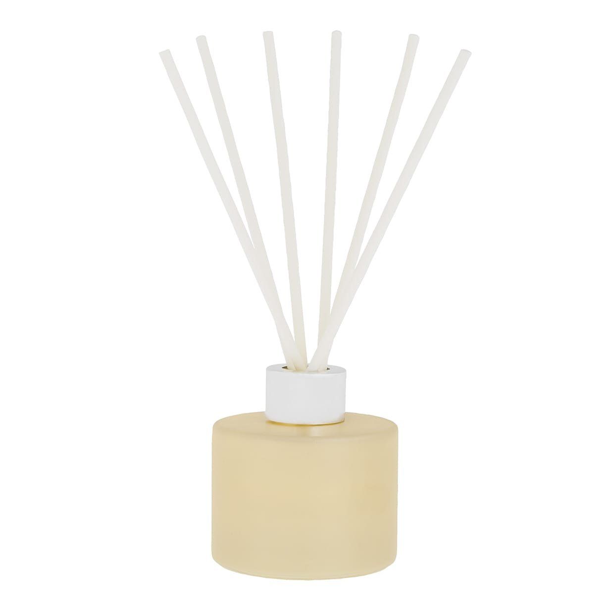Een crèmekleurige geurverspreider met witte rietjes in een lichtgele fles, met de woorden