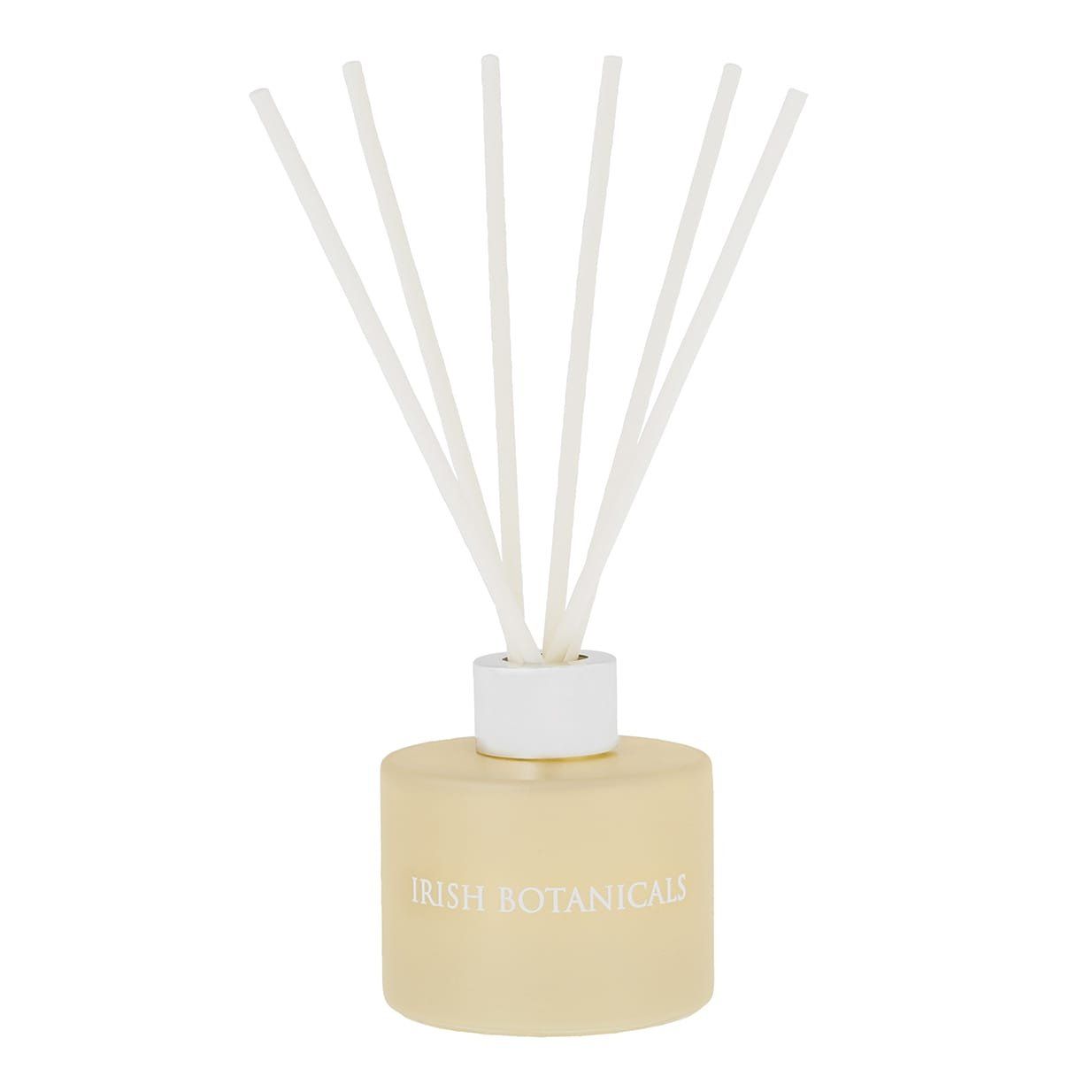 Een crèmekleurige geurverspreider met witte rietjes in een lichtgele fles, met de woorden