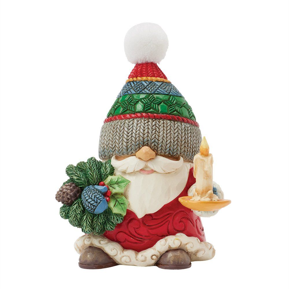 Figuurtje van de Kerstman met een gebreide muts op, een kaars en een kerstkrans in zijn handen.