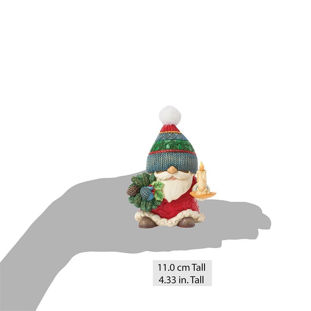 Figuurtje van de Kerstman met een gebreide muts op, een kaars en een kerstkrans in zijn handen.