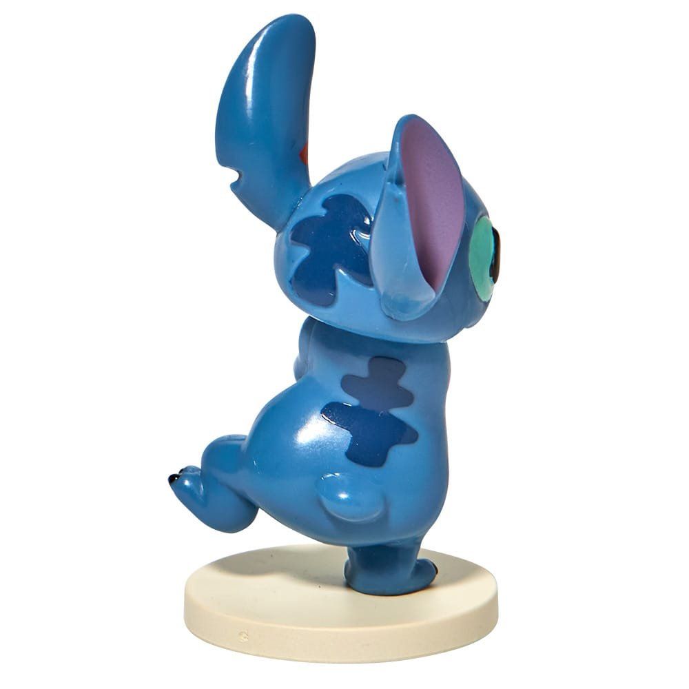 Een blauw Stitch-figuurtje met grote oren en een speelse uitdrukking, staand op een ronde sokkel.