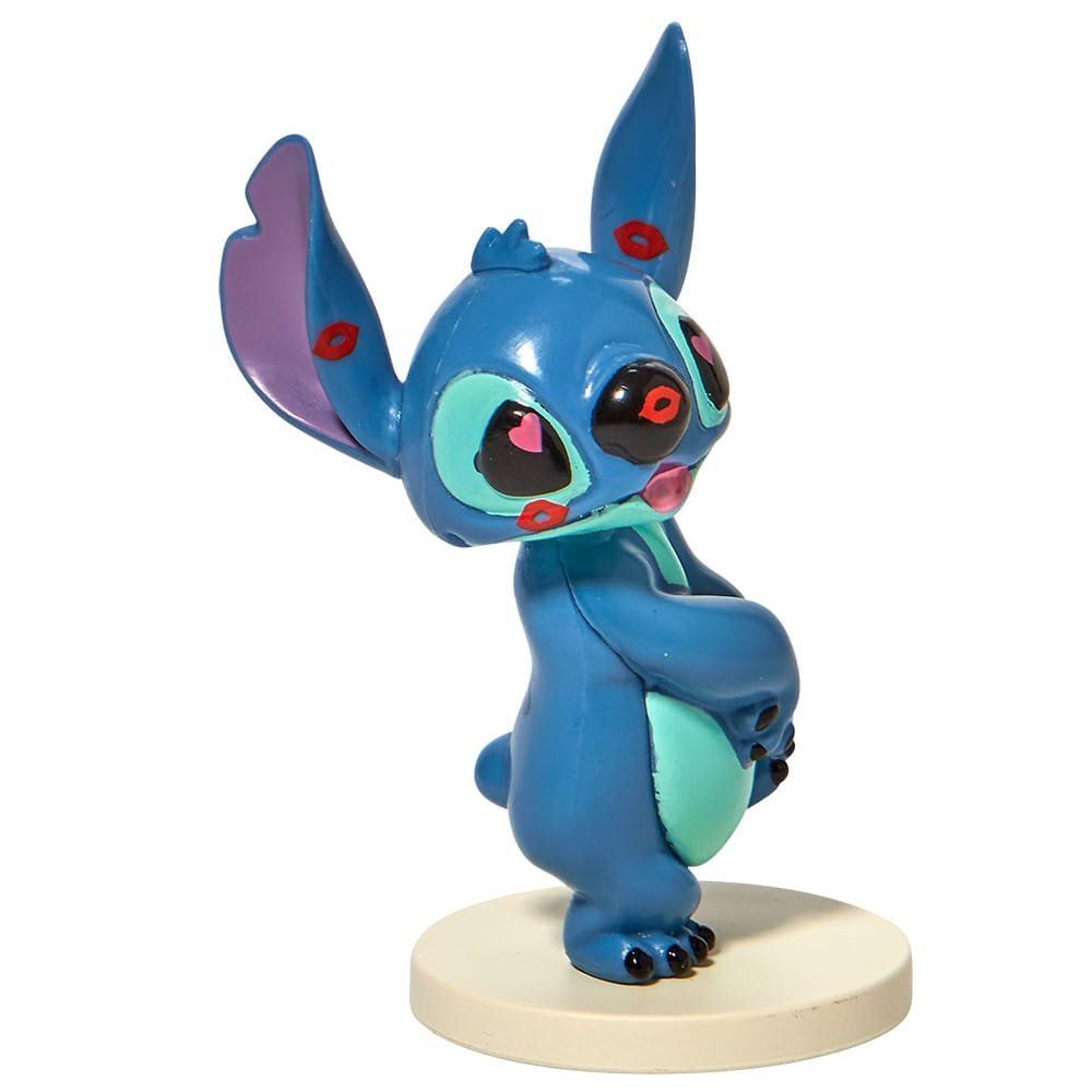 Een figuurtje van Blue Stitch op een crèmekleurige voet, met een speelse uitdrukking.