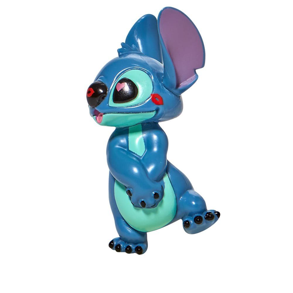 Een Stitch-figuurtje met rode ogen en uitgestoken tong, poserend met één been omhoog, in blauw en turkoois.