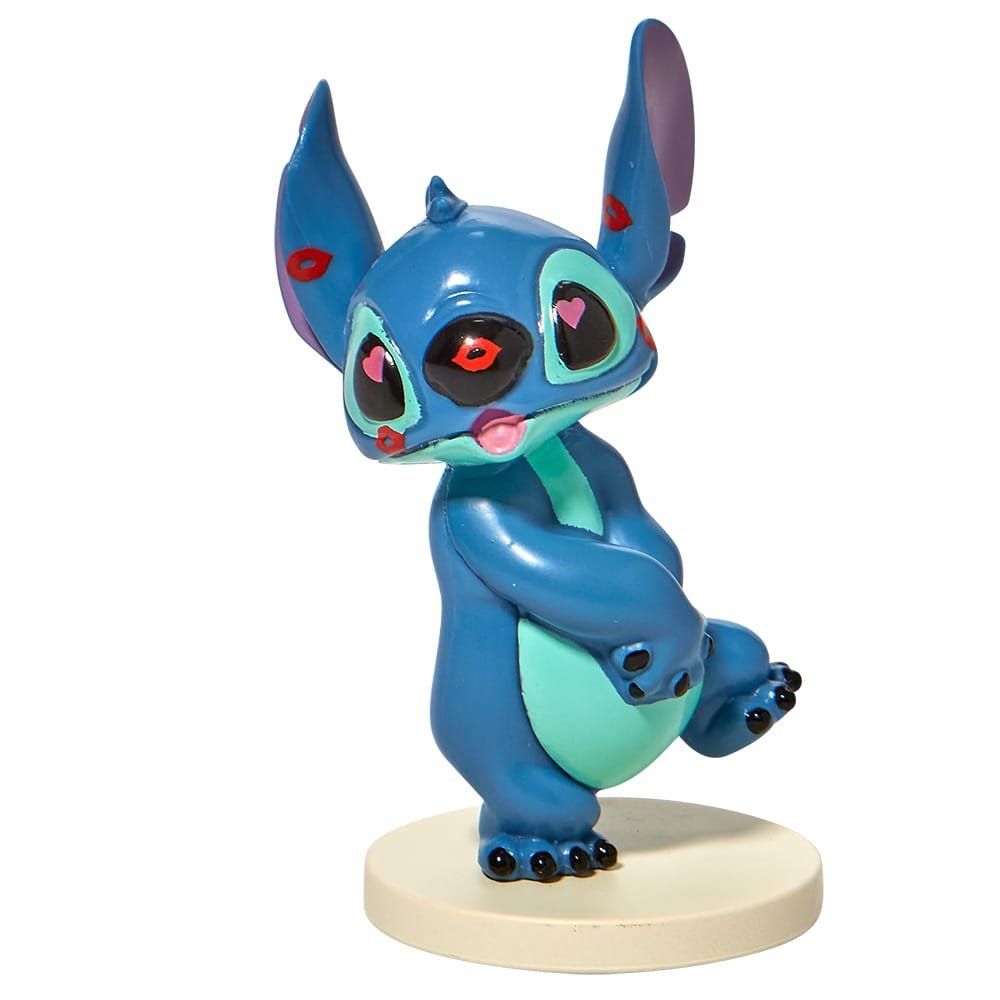 Een blauw Stitch-figuurtje met grote oren en een speelse uitdrukking, staand op een ronde sokkel.