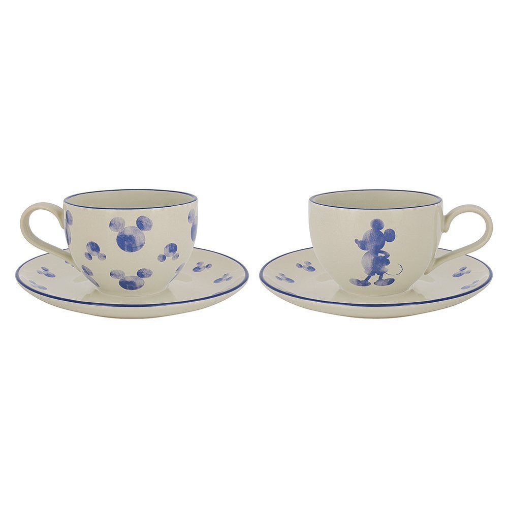 Twee crèmekleurige theekopjes met schoteltjes, versierd met blauwe Mickey Mouse-motieven en -randjes.