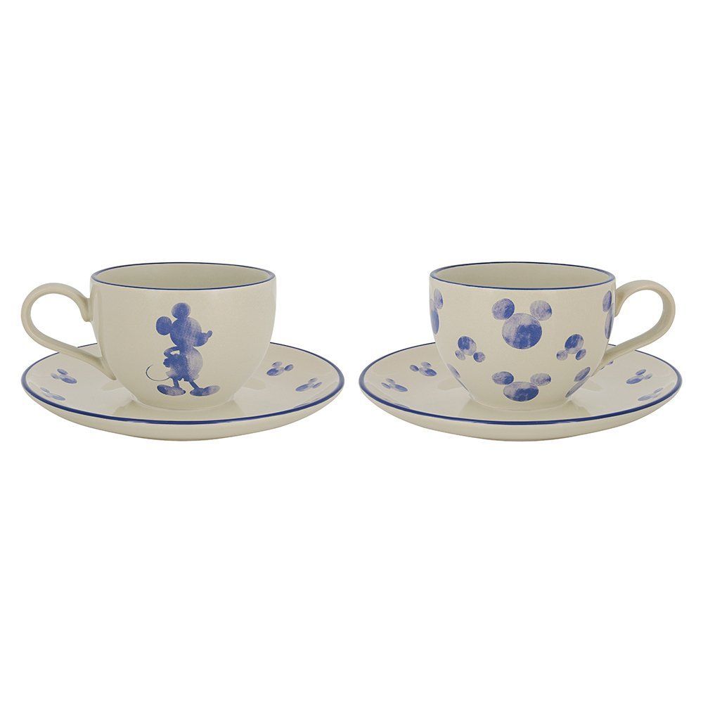 Twee crèmekleurige theekopjes met schoteltjes, versierd met blauwe Mickey Mouse-motieven en -randjes.