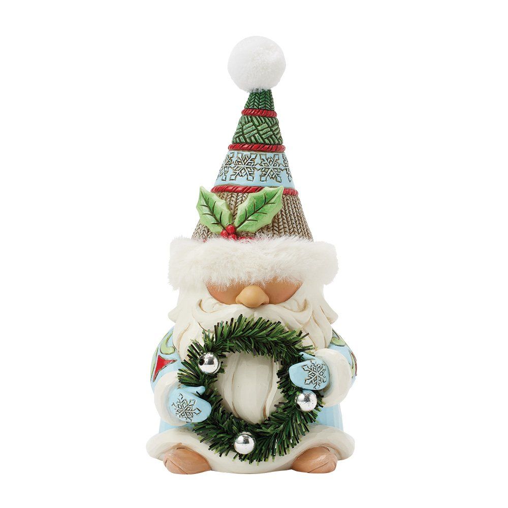 Een kerstkabouterfiguurtje met een hoedje op en een kerstkrans in zijn hand.